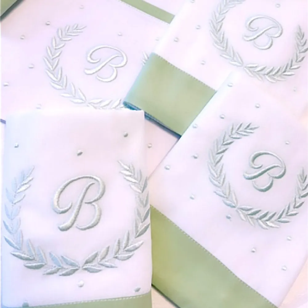 Fraldas com monograma da letra B cercado de ramos, com barra verde